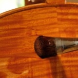 application du vernis sur un violoncelle